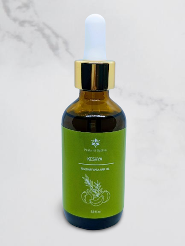 A dark amber bottle filled with Prakriti Sattva Rosemary Amla Hair Ayurvedic Oil. The label features Ayurvedic symbols and herbs, including rosemary, amla, bhringaraj, and licorice, indicating the natural ingredients used.