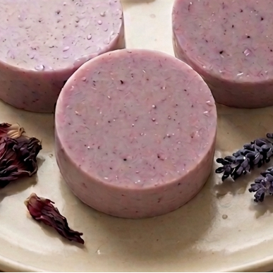 Hibiscus & Lavender Shampoo Bar on a plate with dried hibiscus and lavender flowers, and a dropper bottle.