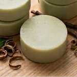Prakriti Sattva botanical hair care products including shampoo bars and a bottle on a wooden surface.