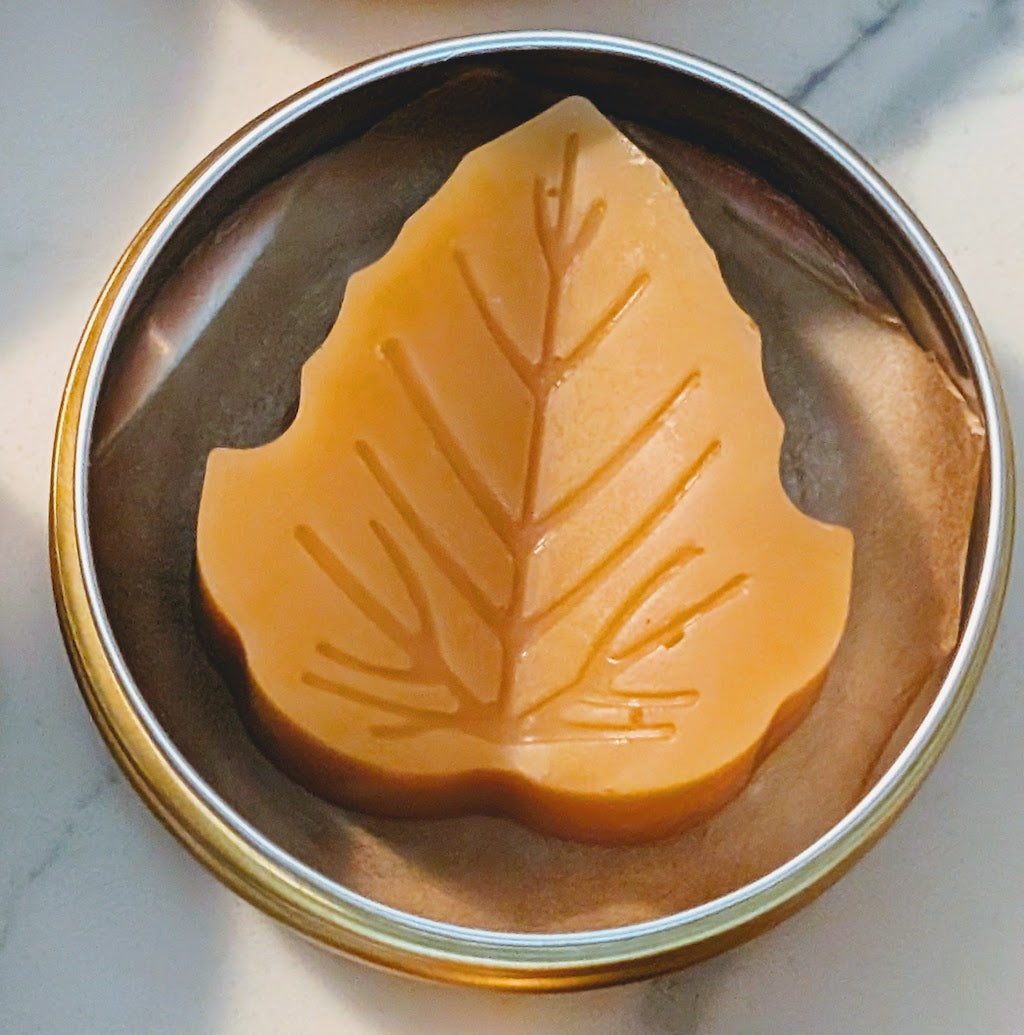 Tin jar of 1 ounce Prakriti Sattva Paduka Lotion bar balm for cracked heels and dry hands in a leaf shape.