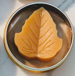 Tin jar of 1 ounce Prakriti Sattva Paduka Lotion bar balm for cracked heels and dry hands in a leaf shape.