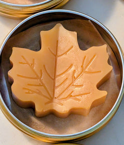 Tin jar of 1 ounce Prakriti Sattva Paduka Lotion bar balm for cracked heels and dry hands in a leaf shape.