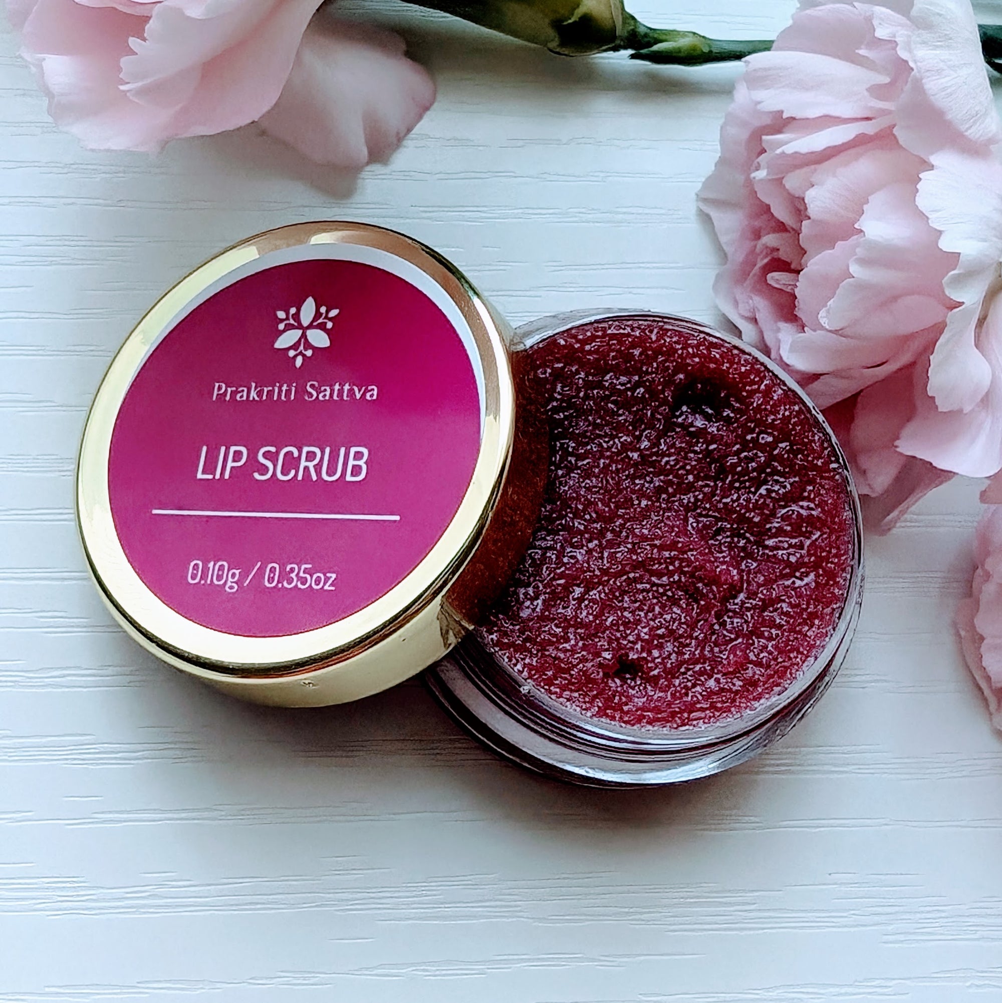 A small container of Prakriti Sattva Ayurvedic Natural Sugar lip scrub in berry color with lid open.