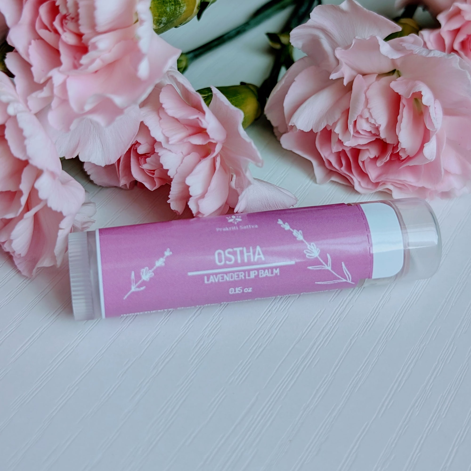 Ayurvedic natural lip balm with alkanet root and lavender essential oil. It is a tube of lip balm with a natural, earthy color. The label features Ayurvedic symbols and herbs, including alkanet root and lavender, indicating the natural ingredients used.